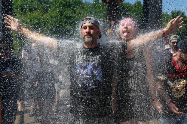 Homme les bras levés se rafraichissant dans un festival